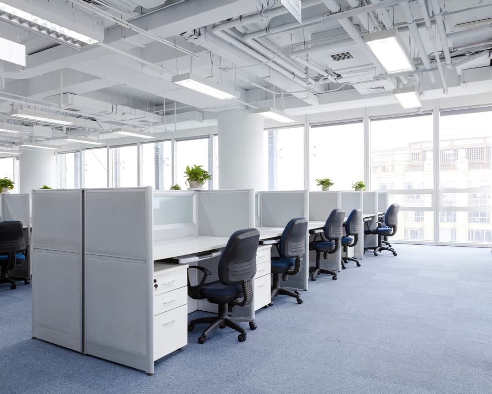 Modern open-plan office with cubicles and chairs.