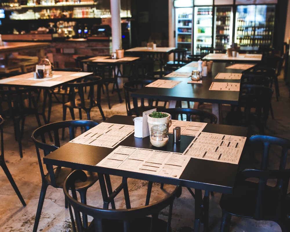 Empty cafe tables with menus and chairs